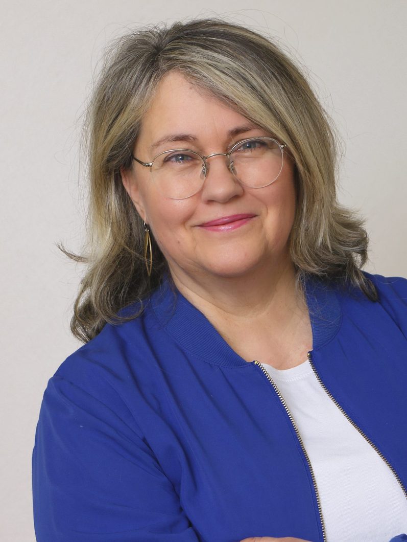 Porträt einer Frau mit Brille und blauer Jacke.